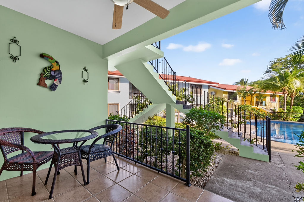 Covered front terrace with wicker chairs overlooking the pool